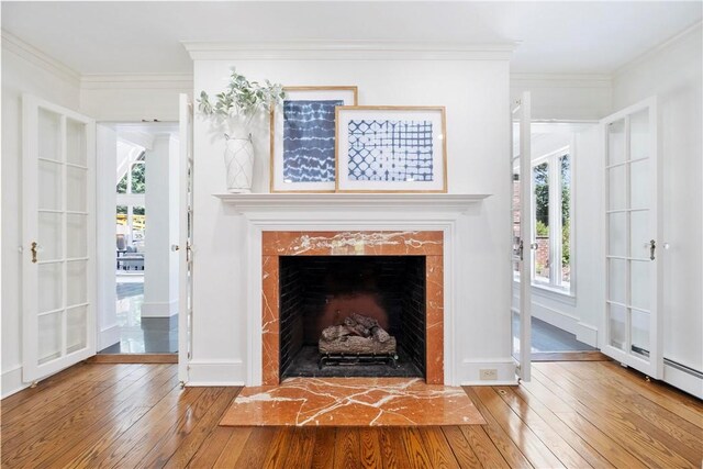 interior space with hardwood / wood-style flooring, a fireplace, crown molding, and french doors