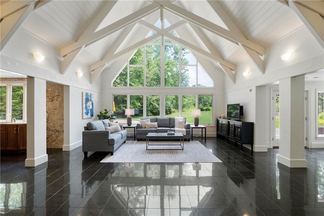 living room featuring beam ceiling, dark tile patterned floors, a healthy amount of sunlight, and high vaulted ceiling