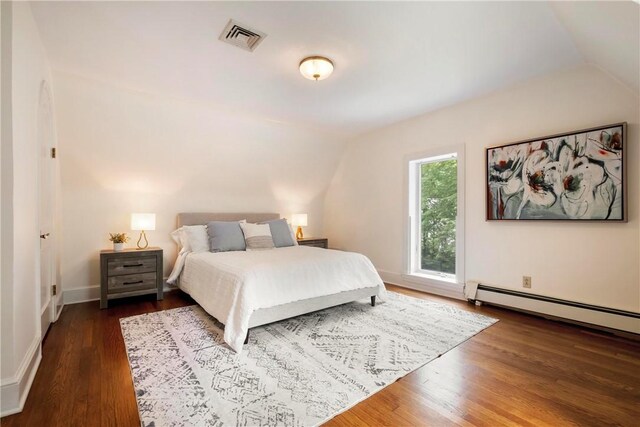 bedroom with dark hardwood / wood-style floors, baseboard heating, and vaulted ceiling