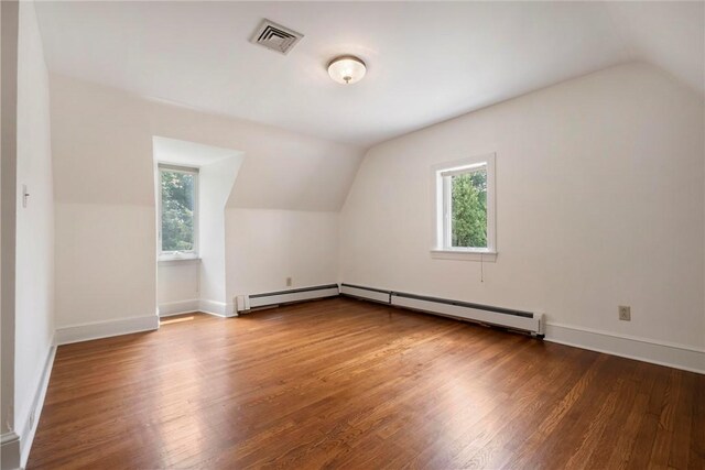 additional living space with a baseboard radiator, lofted ceiling, and hardwood / wood-style floors