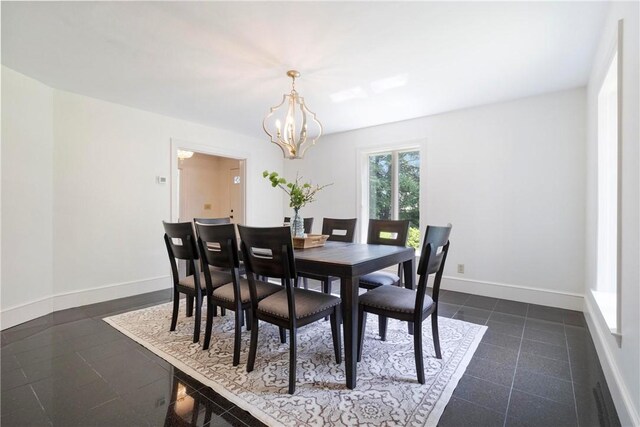 dining area with dark tile patterned floors and a notable chandelier