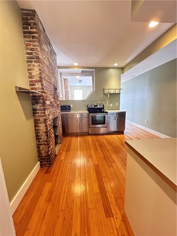 interior space with brick wall, light hardwood / wood-style flooring, and a brick fireplace