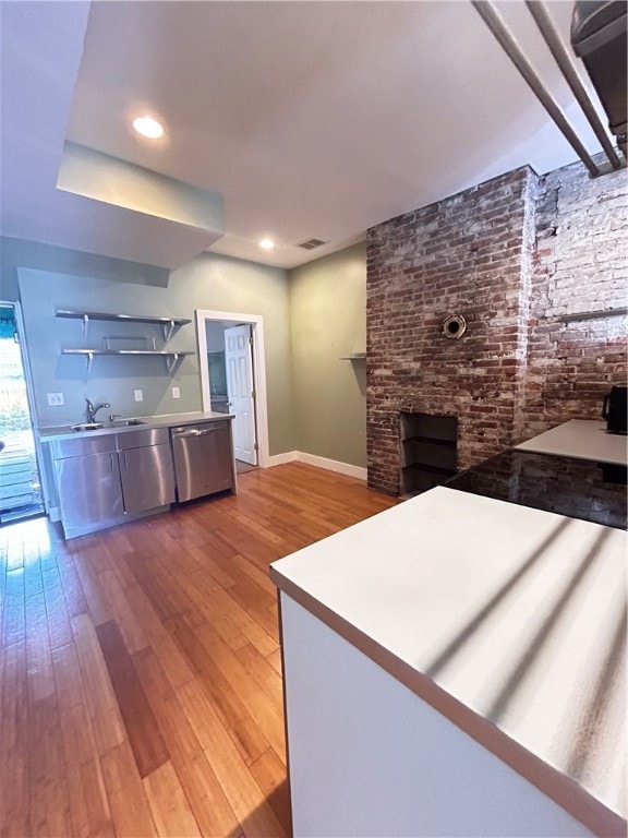 kitchen with sink, a fireplace, dishwasher, and hardwood / wood-style floors