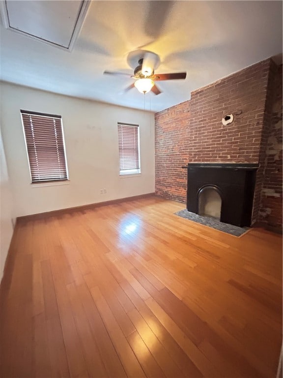 unfurnished living room featuring brick wall, a fireplace, ceiling fan, and hardwood / wood-style floors