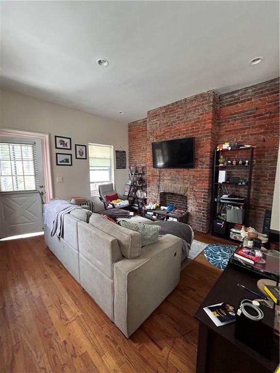 living room with wood-type flooring and a stone fireplace