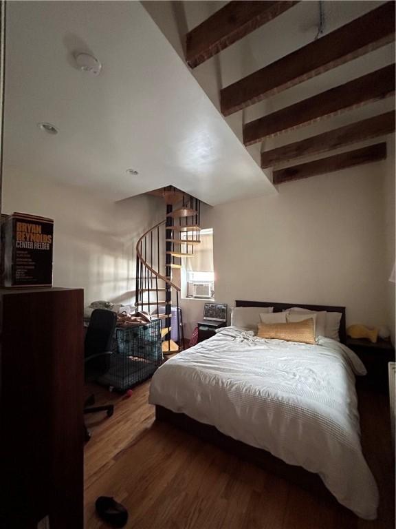 bedroom with beamed ceiling, hardwood / wood-style floors, and cooling unit