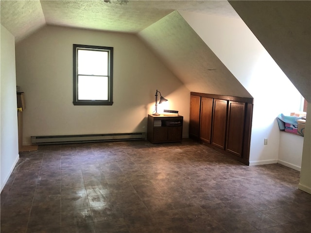 bonus room with dark tile patterned floors, baseboard heating, vaulted ceiling, and a textured ceiling