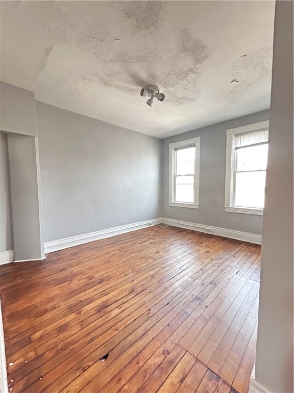 spare room featuring wood-type flooring and a textured ceiling