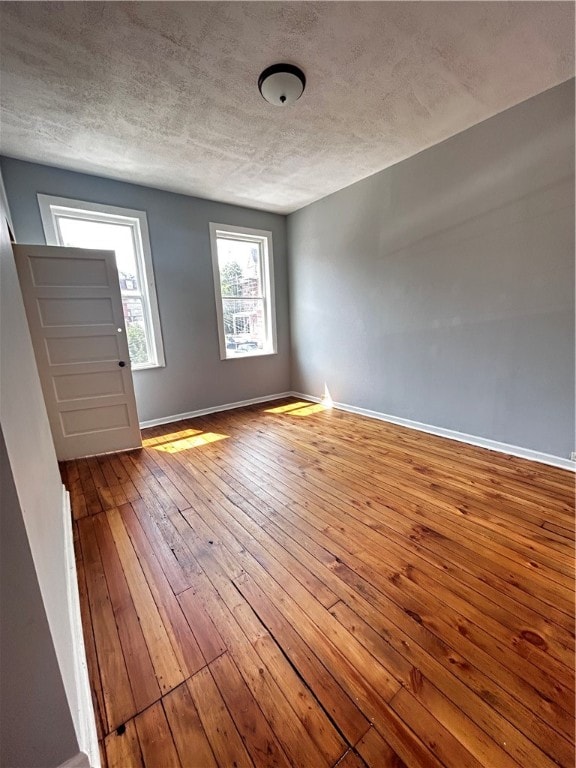 spare room with a textured ceiling and hardwood / wood-style floors