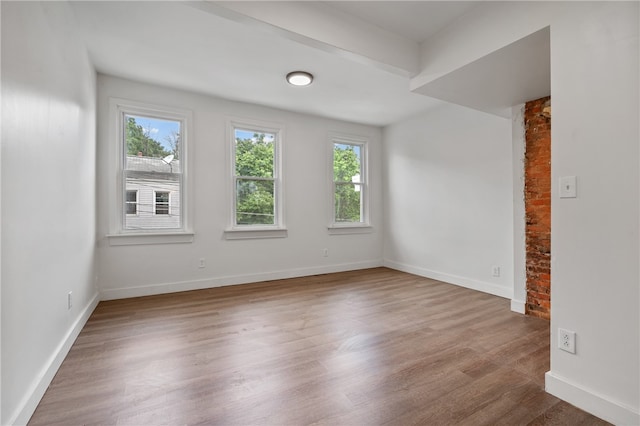 spare room with brick wall and hardwood / wood-style flooring