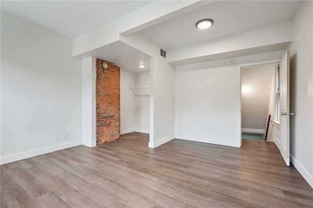 unfurnished room with wood-type flooring and brick wall