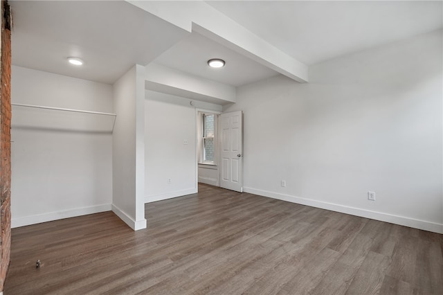 unfurnished bedroom with a closet, beam ceiling, and hardwood / wood-style flooring