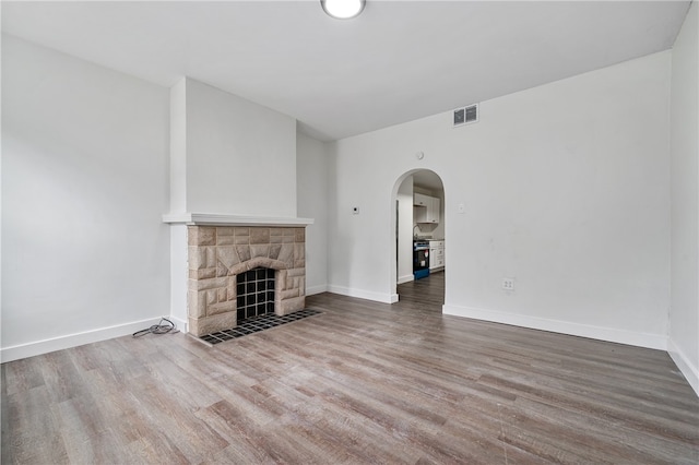 unfurnished living room with a stone fireplace and hardwood / wood-style floors