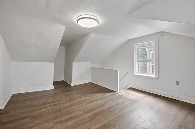 additional living space featuring vaulted ceiling and dark wood-type flooring