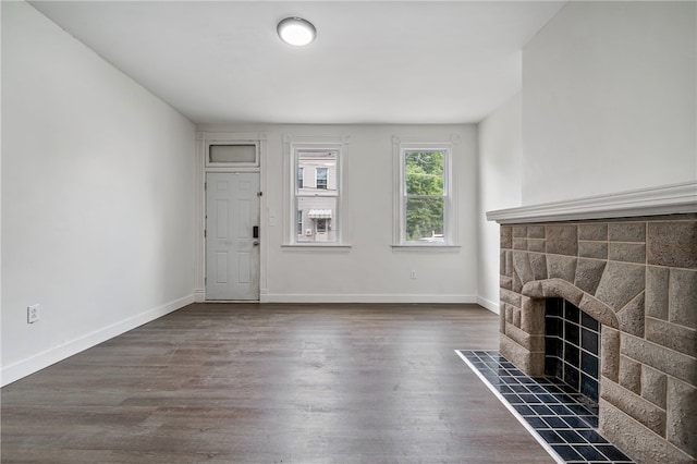 unfurnished living room featuring a tiled fireplace and dark hardwood / wood-style floors