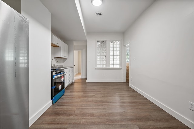 kitchen featuring sink, stainless steel gas stove, fridge, white cabinetry, and dark hardwood / wood-style flooring