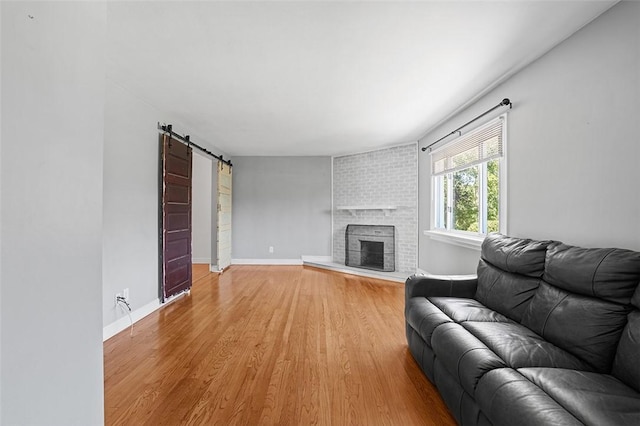 living room with a barn door, hardwood / wood-style floors, and a fireplace