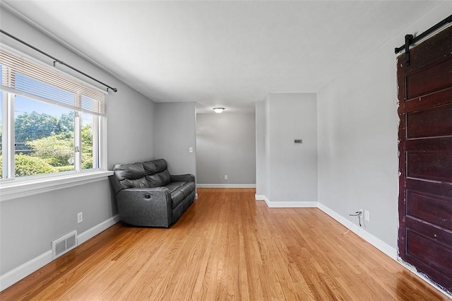 unfurnished room with light hardwood / wood-style flooring and a barn door