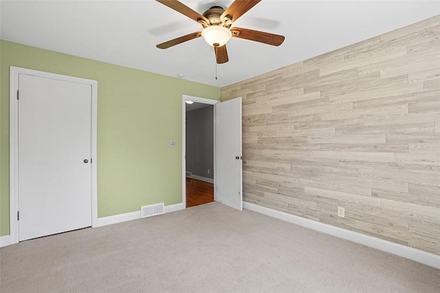 interior space featuring ceiling fan, carpet, and wood walls