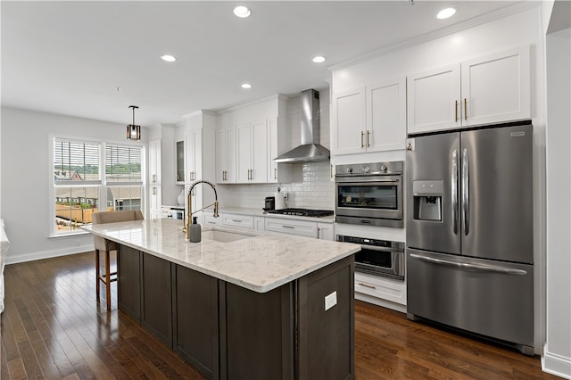 kitchen featuring wall chimney range hood, dark hardwood / wood-style flooring, decorative backsplash, sink, and appliances with stainless steel finishes