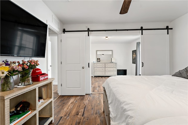 bedroom with ceiling fan, hardwood / wood-style flooring, and a barn door