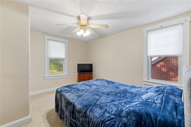 bedroom featuring light carpet, a textured ceiling, and ceiling fan