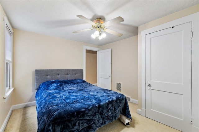 bedroom with light carpet, a textured ceiling, and ceiling fan