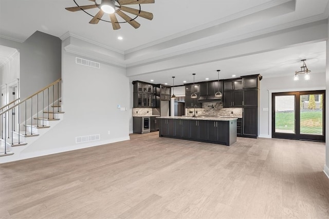 unfurnished living room featuring sink, light wood-type flooring, and crown molding