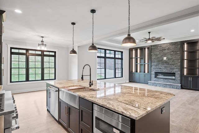 kitchen with a kitchen island with sink, hanging light fixtures, sink, light hardwood / wood-style flooring, and appliances with stainless steel finishes