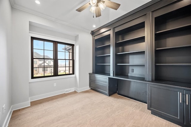 unfurnished office featuring ceiling fan, crown molding, and light wood-type flooring