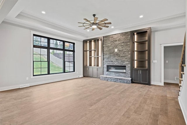 unfurnished living room with a fireplace, light wood-type flooring, ceiling fan, and ornamental molding