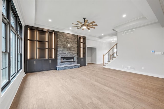 unfurnished living room with light hardwood / wood-style flooring, ceiling fan, a stone fireplace, and crown molding