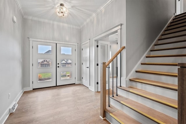 entryway with an inviting chandelier, crown molding, light hardwood / wood-style flooring, and french doors