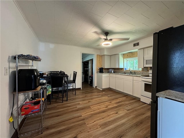 kitchen featuring hardwood / wood-style floors, white appliances, white cabinets, sink, and ceiling fan