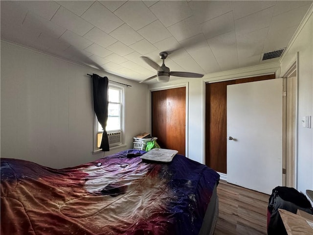 bedroom with ceiling fan, cooling unit, and hardwood / wood-style flooring