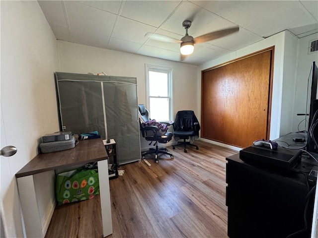 office featuring ceiling fan, a drop ceiling, and hardwood / wood-style flooring