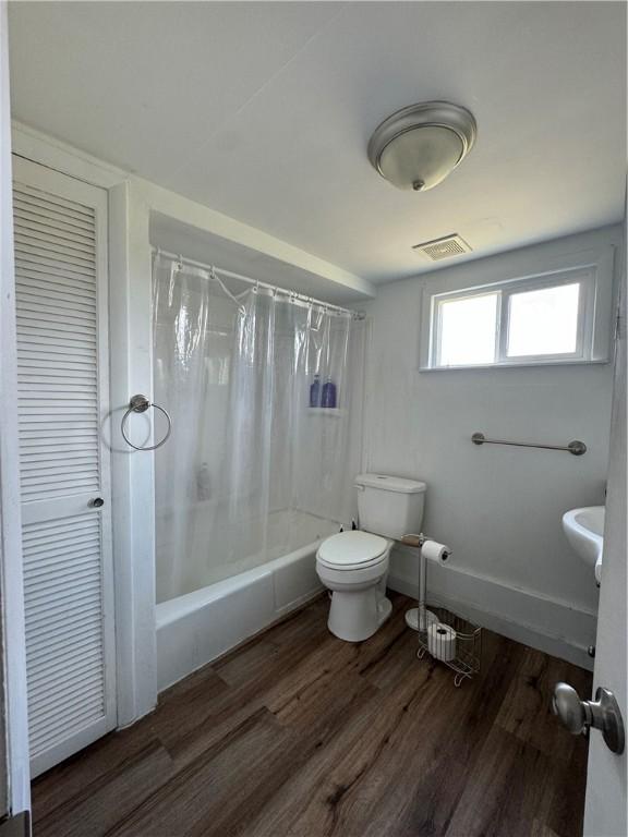 bathroom featuring shower / bath combo, hardwood / wood-style flooring, and toilet