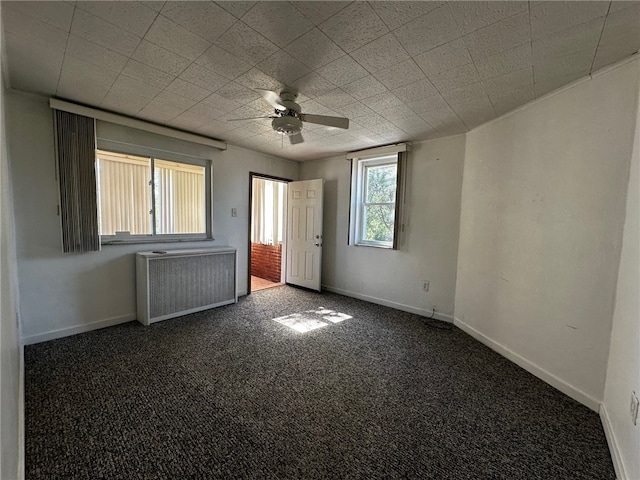 unfurnished bedroom with radiator, dark colored carpet, and ceiling fan