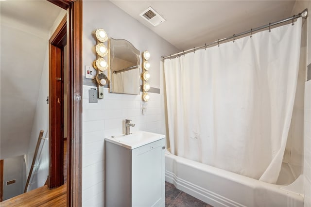 bathroom featuring tile patterned flooring, tile walls, shower / tub combo, and vanity