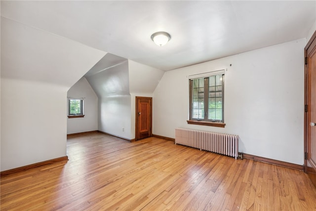 additional living space featuring vaulted ceiling, light hardwood / wood-style flooring, and radiator heating unit