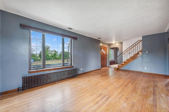 unfurnished living room with radiator and light hardwood / wood-style flooring