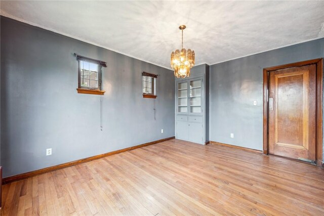 unfurnished room with light wood-type flooring and a notable chandelier