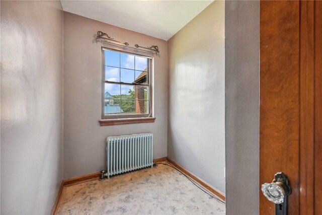 empty room featuring radiator heating unit and carpet flooring