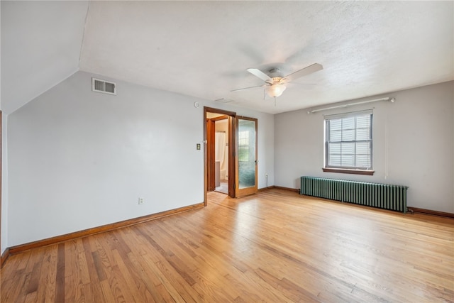 empty room featuring lofted ceiling, radiator, light hardwood / wood-style flooring, and ceiling fan