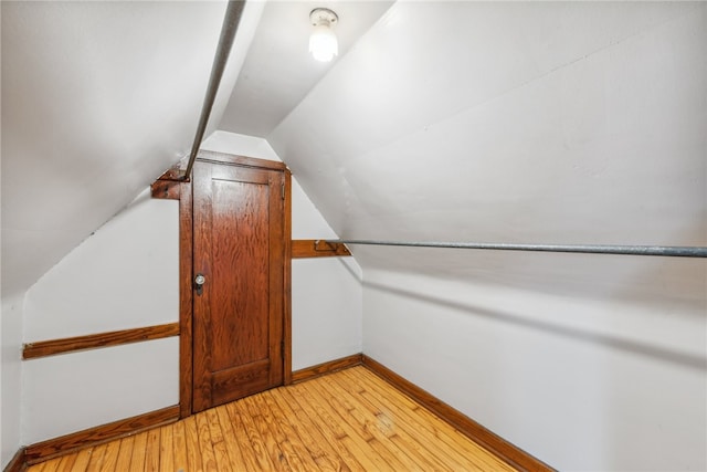 additional living space featuring vaulted ceiling and light wood-type flooring