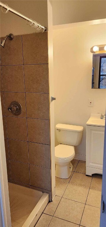 bathroom featuring tiled shower, tile patterned floors, vanity, and toilet