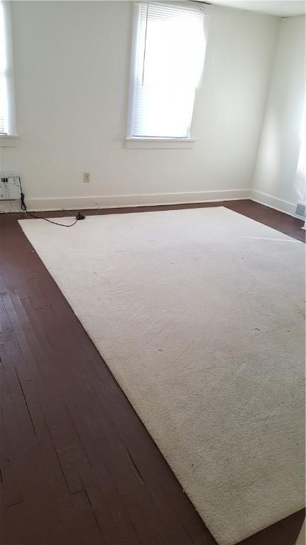 empty room with a healthy amount of sunlight and dark hardwood / wood-style flooring