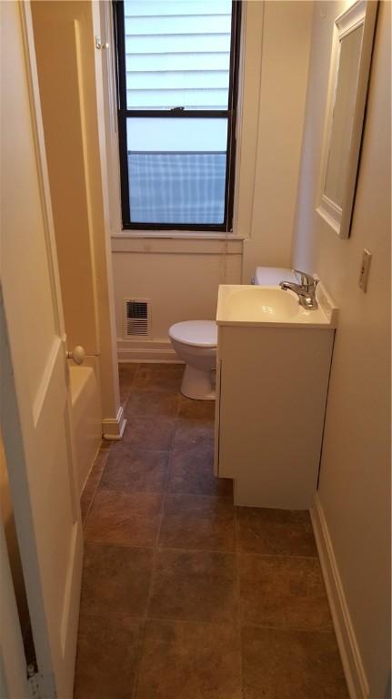 bathroom with a tub, vanity, and toilet