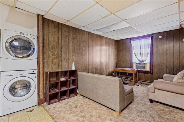 interior space featuring stacked washer and clothes dryer, light colored carpet, and wood walls