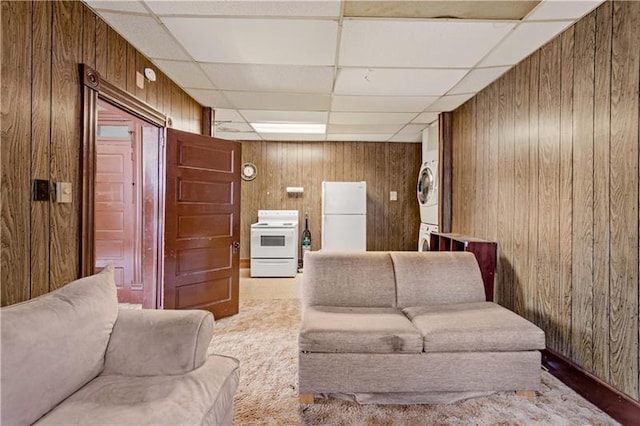 interior space with a drop ceiling, stacked washer and dryer, and wooden walls